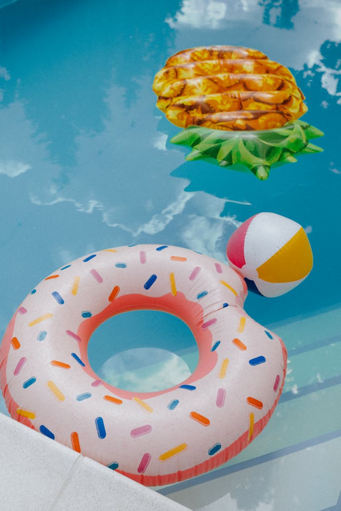 Bright inflatables in a summer pool setting with a donut ring and pineapple float.